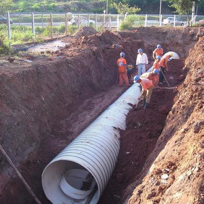 Tubo de PVC estruturado BR Loc assentado em vala de drenagem, com equipe compactando a envoltoria granular